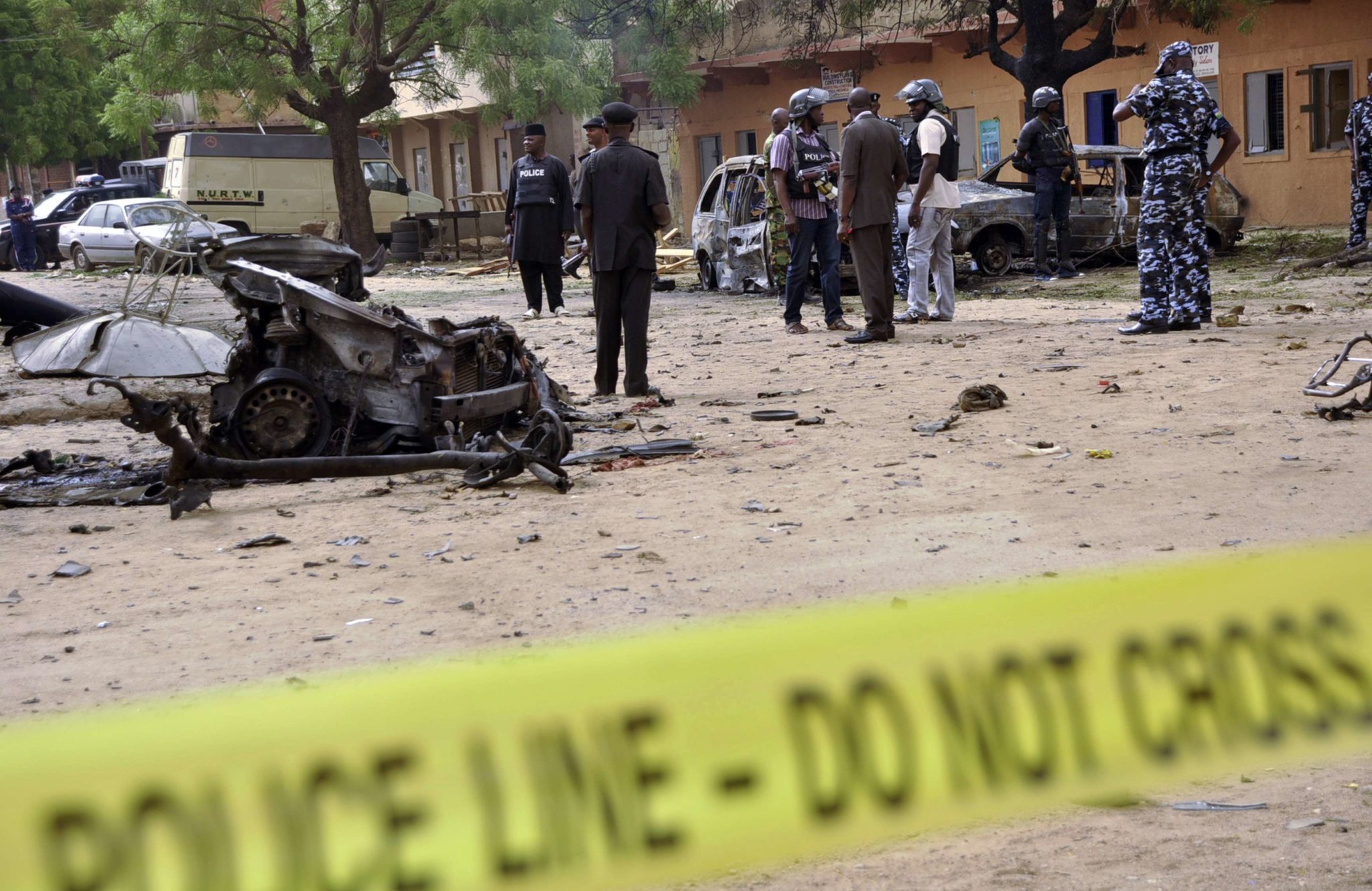 Policemen stand near damaged vehicles in Sabon Gari, Kano