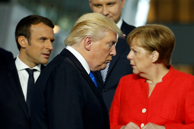 U.S. President Trump walks past French President Macron and German Chancellor Merkel on his way to his spot for a family photo during the NATO summit at their new headquarters in Brussels